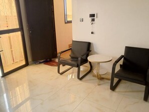 A room with two black chairs, a small round table, and a door leading outside.
