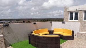 Um terraço no telhado com uma área de estar curva ao ar livre e vista para a paisagem.