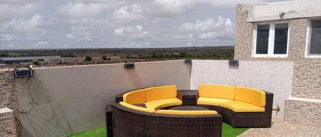 Une terrasse sur le toit dotée d’un espace salon extérieur aux lignes courbes et offrant une vue sur le paysage.