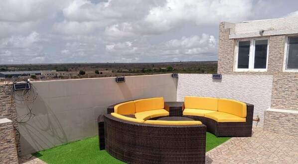 A rooftop patio with a curved outdoor seating area and a view of the landscape.