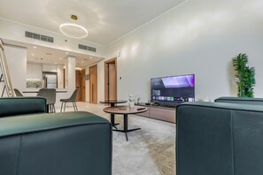 Een moderne woonkamer met een flatscreen televisie, comfortabele zitplaatsen en een decoratieve plant.