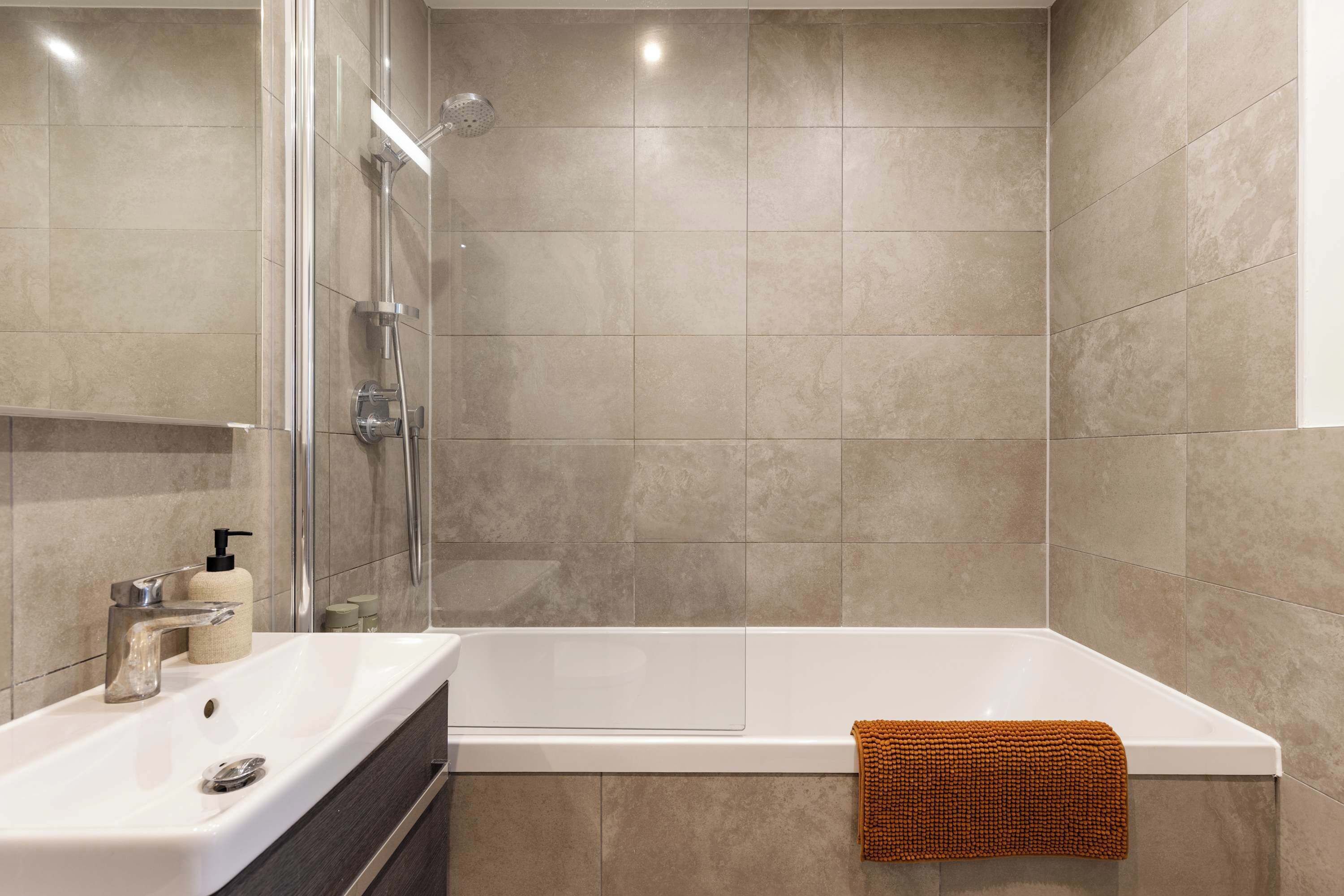 Ein modernes Badezimmer mit Badewanne, Glasdusche und Waschtisch.