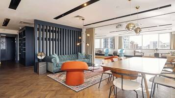 A modern interior with a seating area, a dining table, and a large window offering a city view.