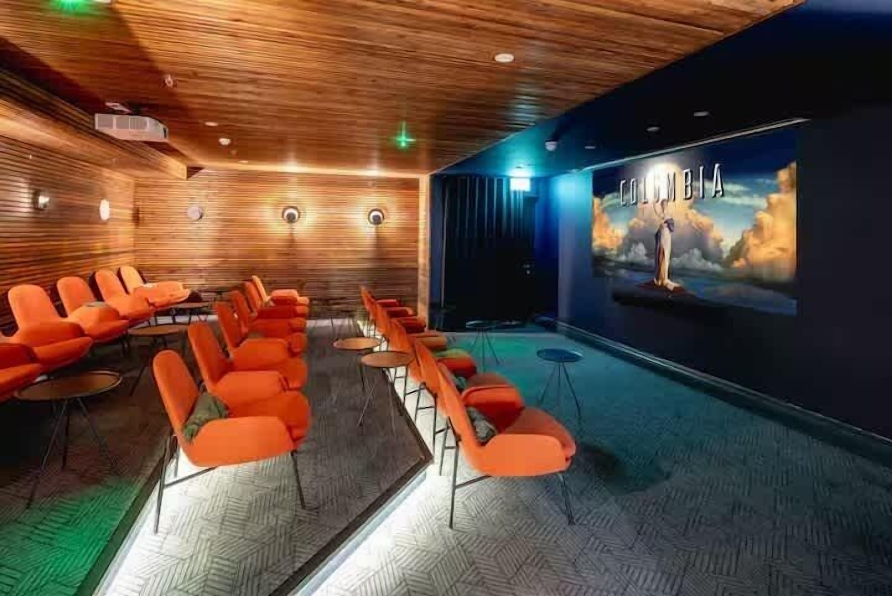 Een bioscoopzaal met rijen oranje zitplaatsen en een groot scherm waarop 'Columbia' staat.