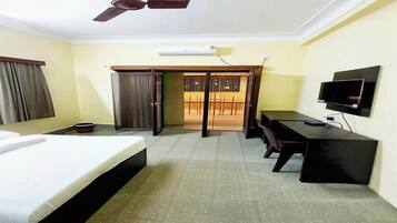 A hotel room with a bed, desk, television, and a ceiling fan.