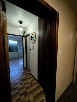 A hallway with a checkered floor, a door with a mirror, and a light fixture. - TURCKHEIM: A HAVEN OF PEACE (Turckheim)