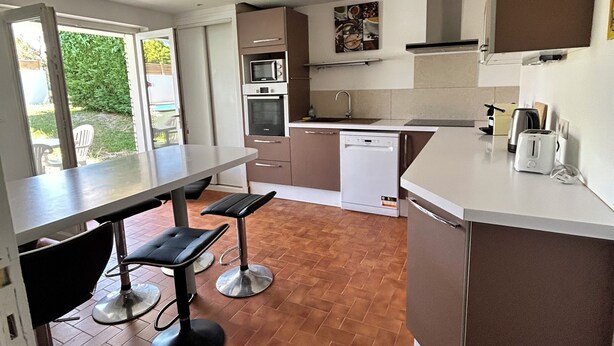 Uma cozinha moderna com área de refeições, incluindo uma mesa e dois banquetes.