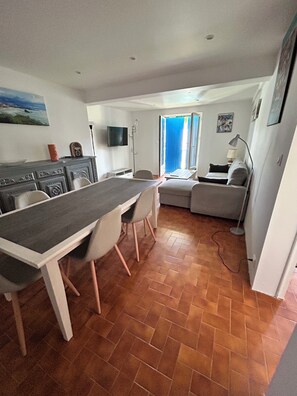 A compact living space with a dining area, a sofa, and a television. - Fully renovated 2-bedroom apartment near the beach (Bidart)