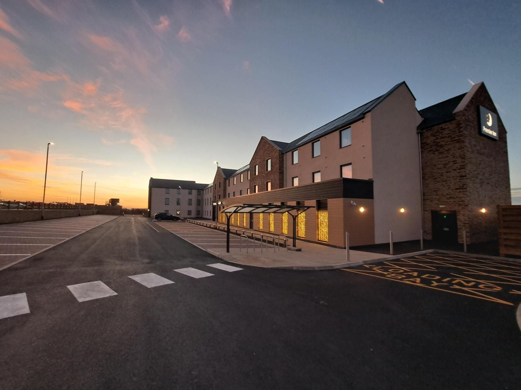 A modern building with a covered walkway and a parking area.