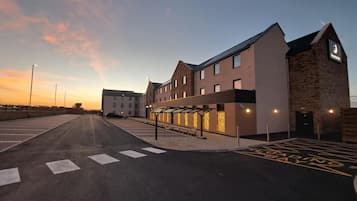 A modern building with a covered walkway and a parking area.