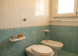 Een badkamer met twee toiletten, een wastafel en een raam.
