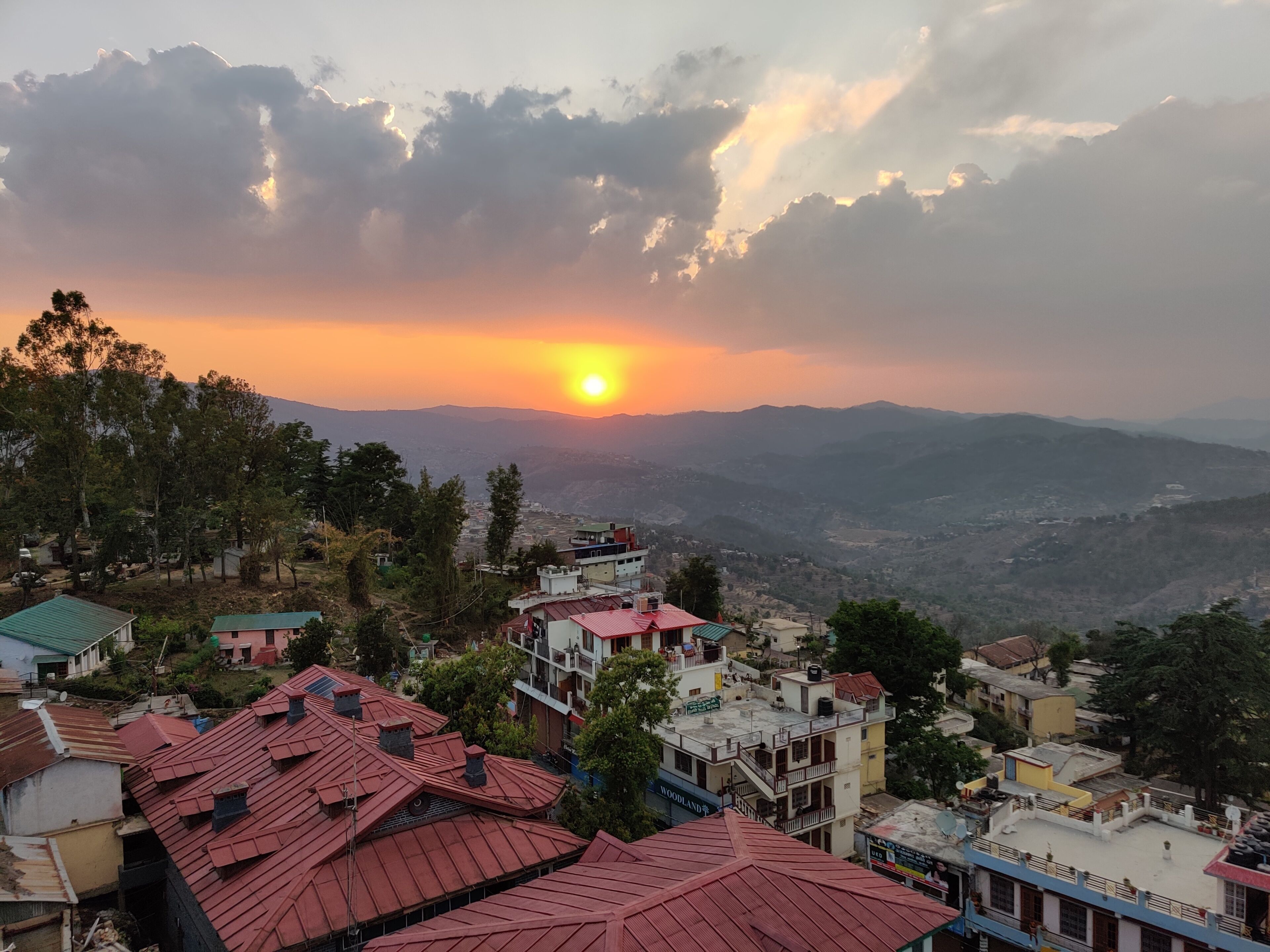 Un barrio residencial con casas y vistas al atardecer sobre un paisaje montañoso.