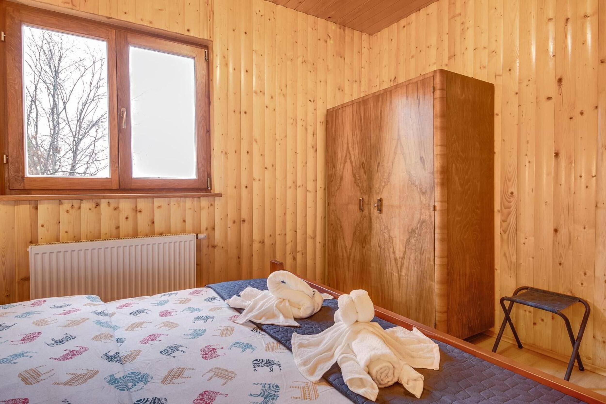 Une pièce en bois avec un lit, une armoire et une fenêtre.