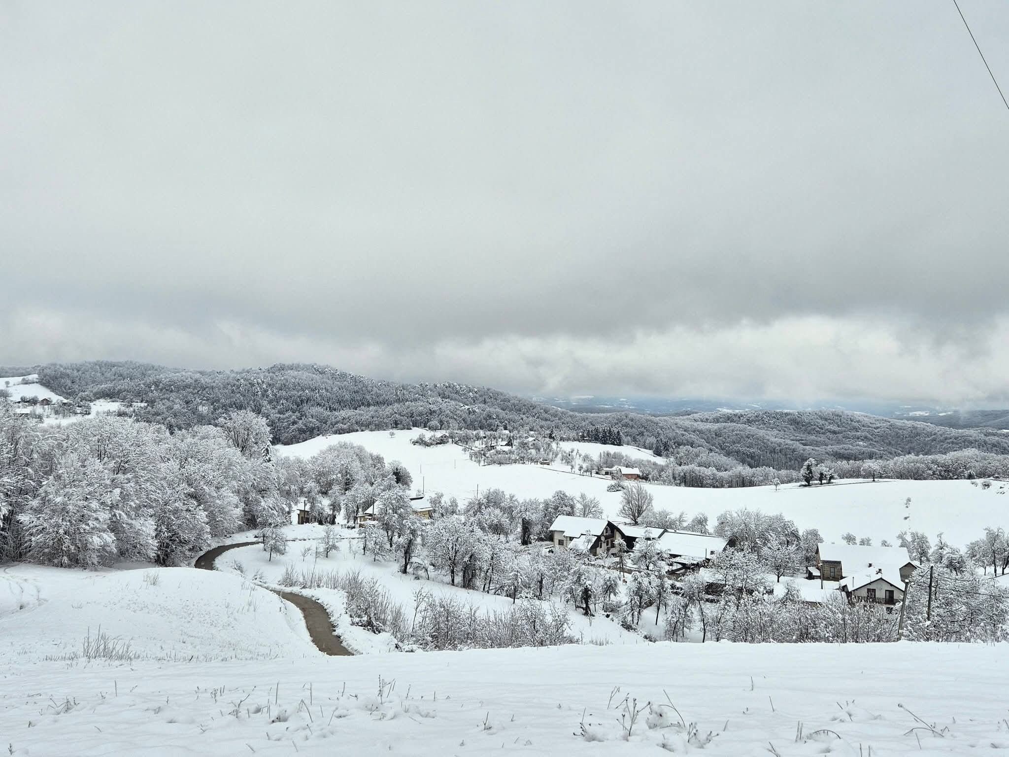 Paesaggio innevato con case e un fiume.