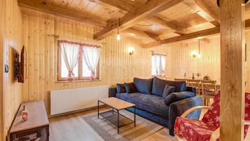Un accogliente interno in legno con un divano, un tavolino e un termosifone.
