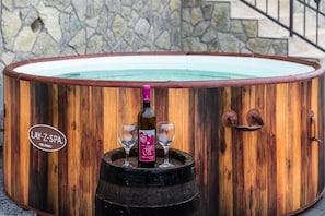 Una vasca idromassaggio in legno con l'etichetta 'LAY-Z-SPA' e una bottiglia di vino.