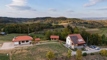 Ländliche Landschaft mit einem Haus, das ein rotes Ziegeldach und eine Solaranlage hat.