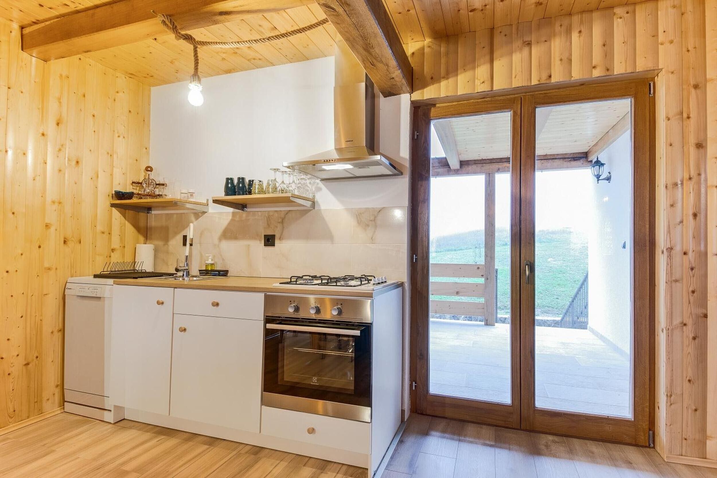 Un intérieur en bois comprenant un espace cuisine, avec un poêle, un four et des placards.