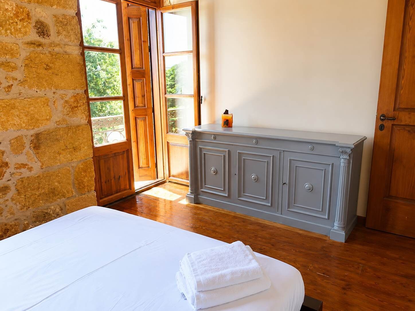 Une pièce avec un lit, une armoire grise et une porte en bois.