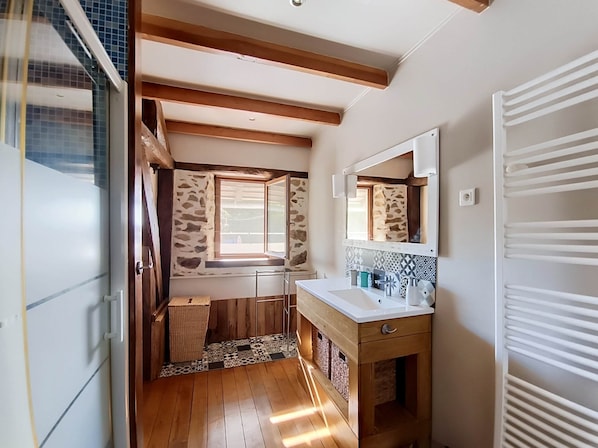 A compact bathroom with a wooden vanity, a mirror, and a window with a view.