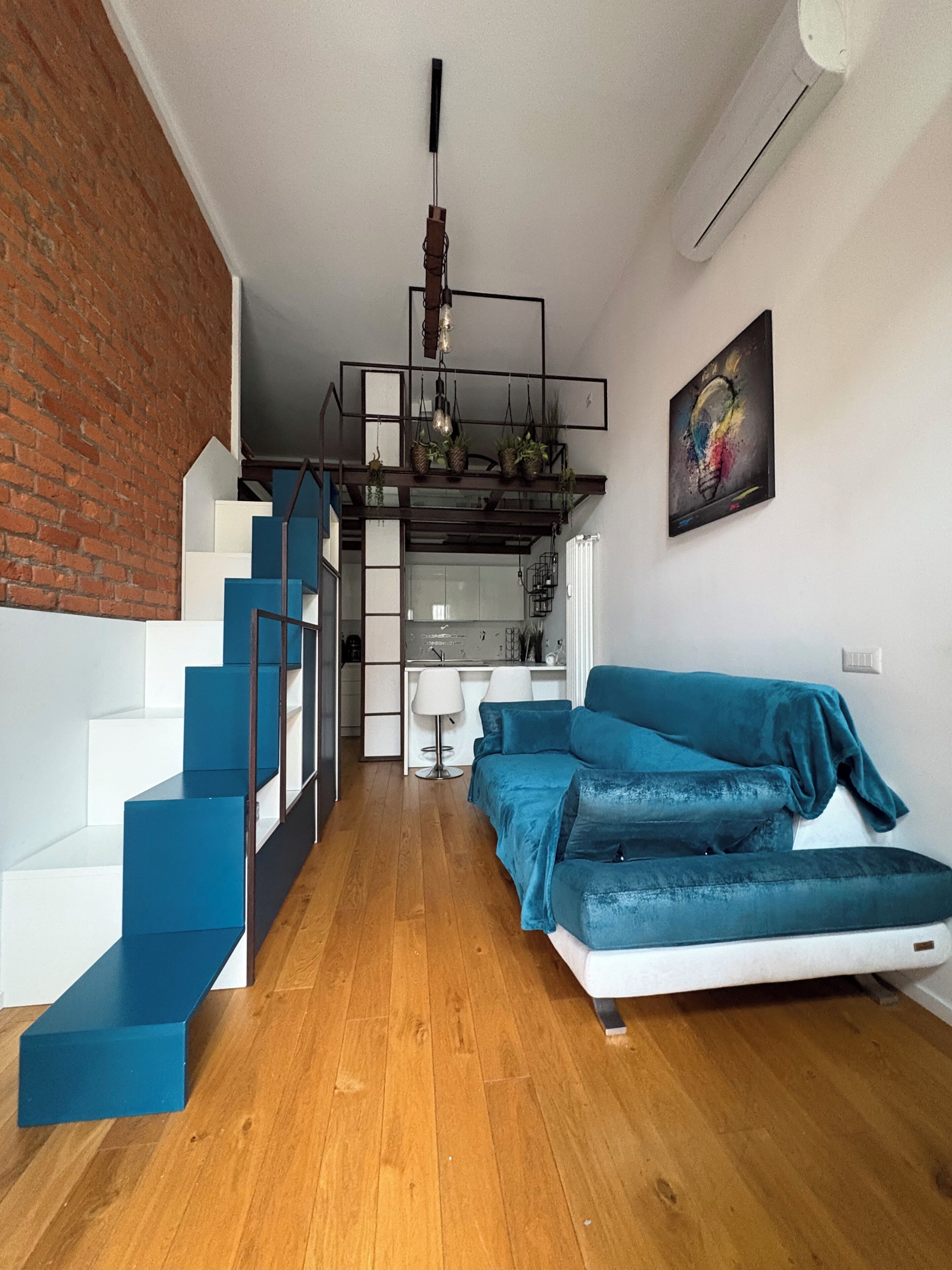 A modern interior with a staircase, a sofa, and a kitchen area.