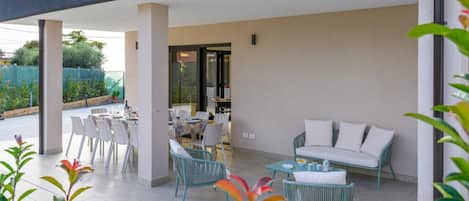 An outdoor patio area with a dining table and chairs, a sofa, and a small table with a vase.