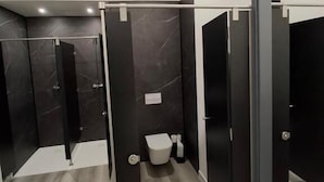 Un baño moderno con ducha, inodoro y mampara de vidrio.