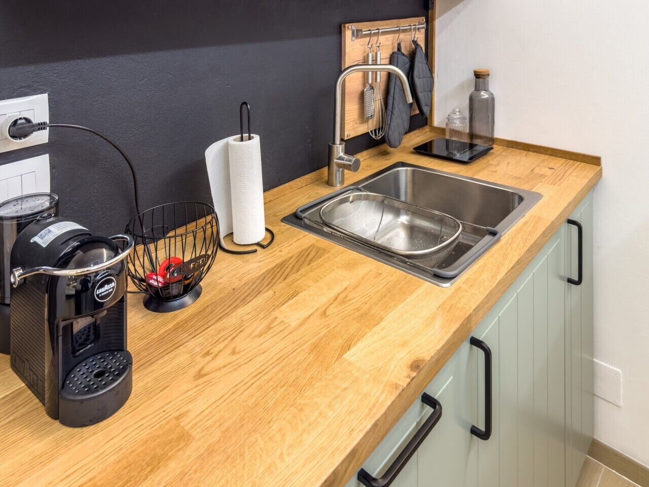 A kitchen with a coffee maker, a paper towel holder, a sink, and a spice rack.
