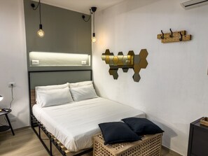 Une chambre à coucher moderne, comprenant un lit, une table de chevet, une lampe fixée au mur et des œuvres d’art décoratives accrochées au mur.