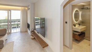 A modern hotel room with a balcony, a flat-screen TV, a large mirror, and a wooden side table. - Chic Athenian Riviera Retreat in Vari  (Vari)
