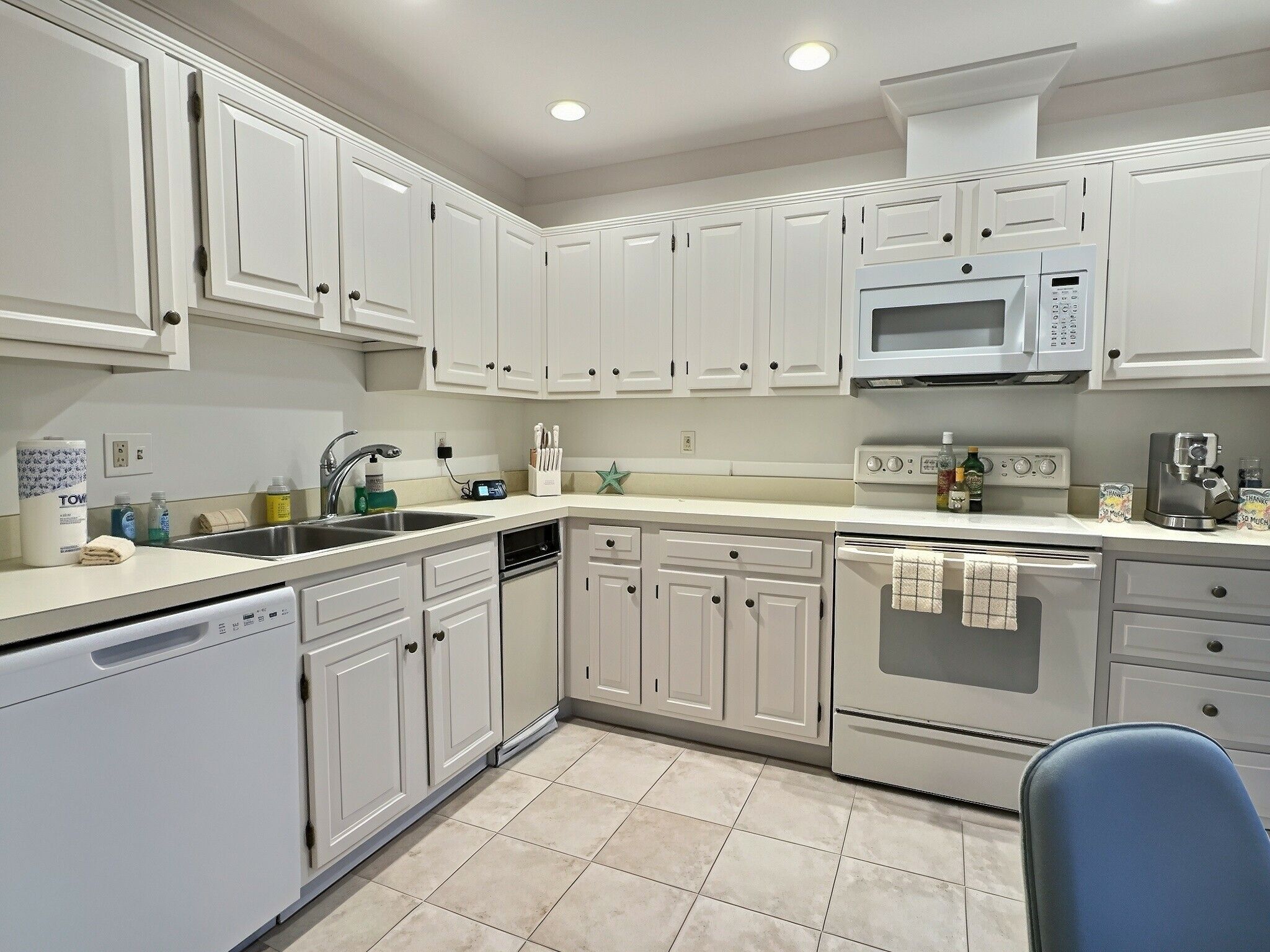 A kitchen with white cabinets, a dishwasher, a microwave, and a stove.