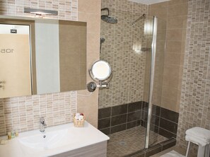Un baño con ducha, lavabo y espejo.