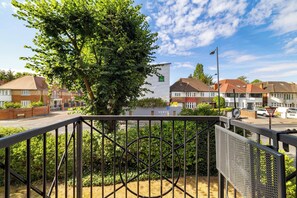 A residential area with houses, a large tree, and a building with a sign. - Green Light in Brondesbury Park (Greater London)