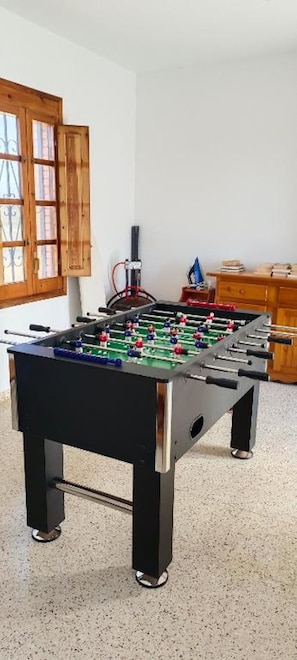 A foosball table in a room with a wooden door and a dresser.