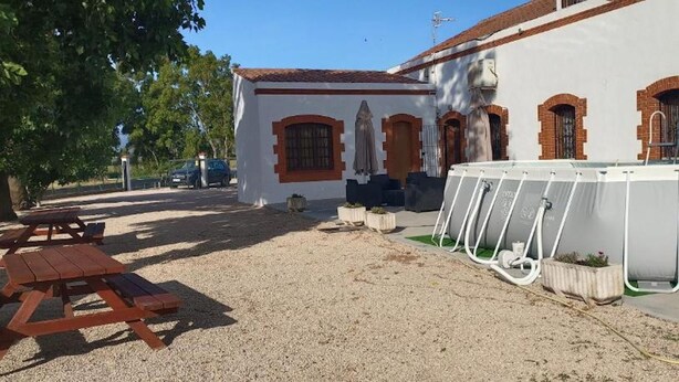 A building with a white exterior, red brick arches, and a pool area with a water filtration system.