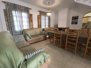 Ein Wohnzimmer mit einer Couch, einem Esstisch, Stühlen und einer Hängelampe.