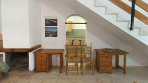 A room with a fireplace, wooden furniture, a staircase, and a view into another room.