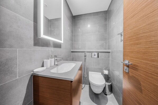 Ein modernes Badezimmer mit einem Holzkonsolenunterschrank, einem Waschbecken, einer Toilette und einer Dusche.