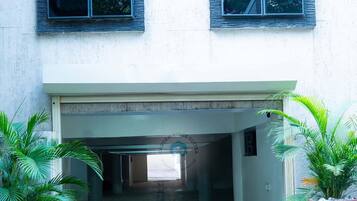 Entrada de un edificio con un camino despejado que conduce al interior, flanqueada por plantas en macetas.