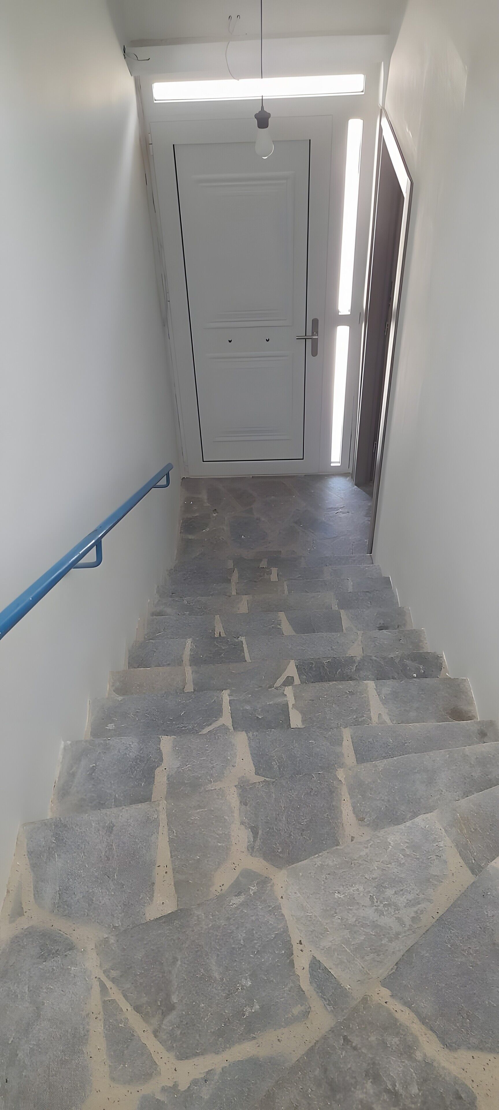 A staircase with stone steps leading to a door with a handle and a keyhole.