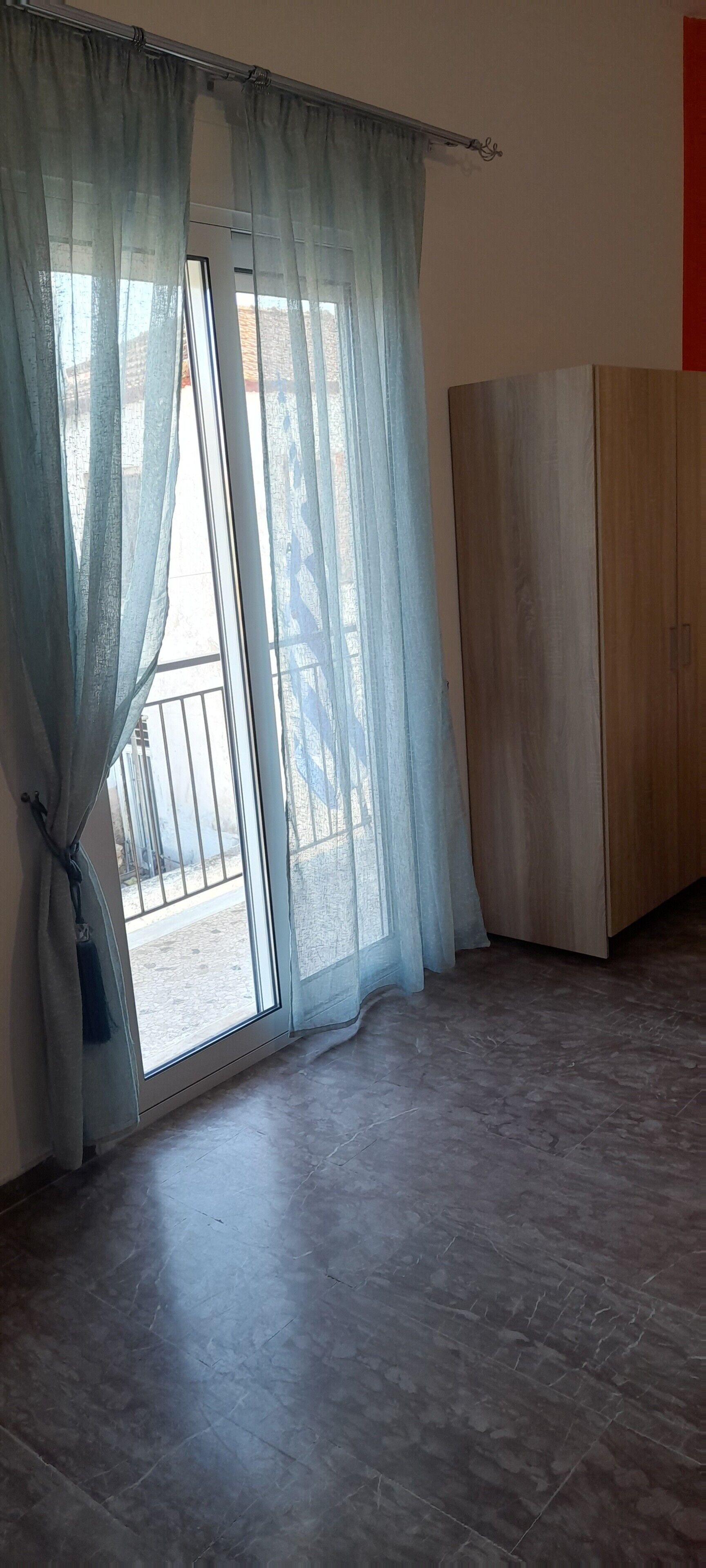 A room with a sliding glass door, a wooden wardrobe, and a tiled floor.