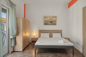 A hotel room with a bed, a nightstand, a wooden wardrobe, and a painting on the wall.