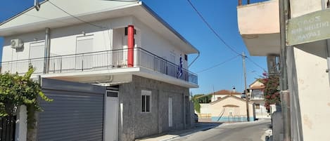 A residential building with a balcony, a garage, and a clear sky.