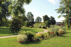 Un jardin bien entretenu, avec un sentier sinueux, différents arbustes et arbres.