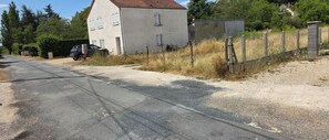 Une route de campagne avec un bâtiment blanc et une voiture garée.
