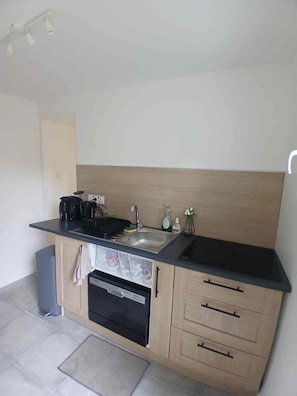 A compact kitchen with a black countertop, a built-in oven, a sink, and a small cabinet with drawers. - A quiet house within a 15-minute walk of the train station, close to Disney and Paris (Lagny-sur-Marne)
