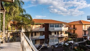 A multi-story residential building with balconies, a tiled roof, and a clear sky. - Casa Daniela by Wonderful Italy (Aci Castello)