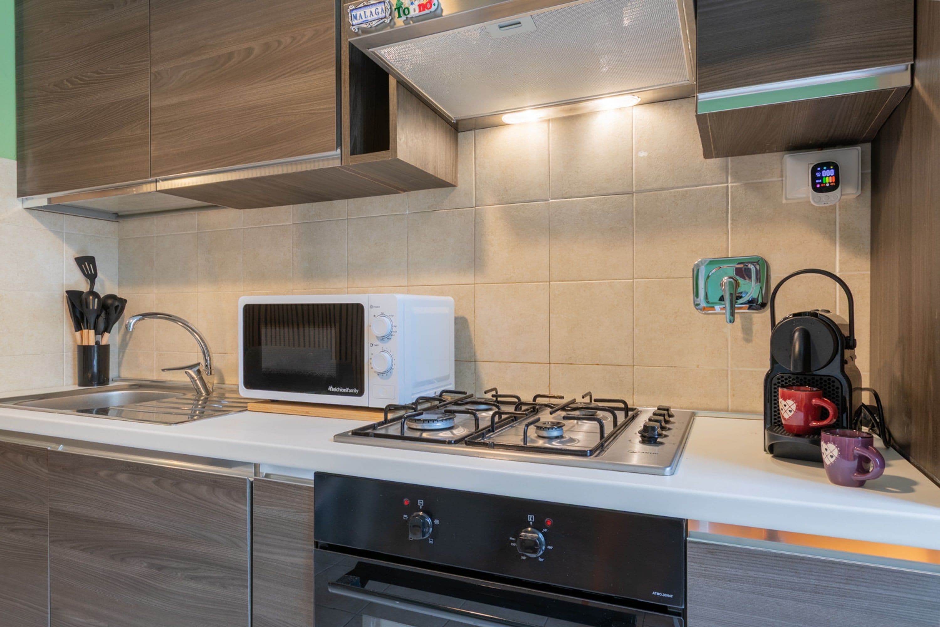 A compact kitchen with a microwave, gas stove, and a coffee maker.