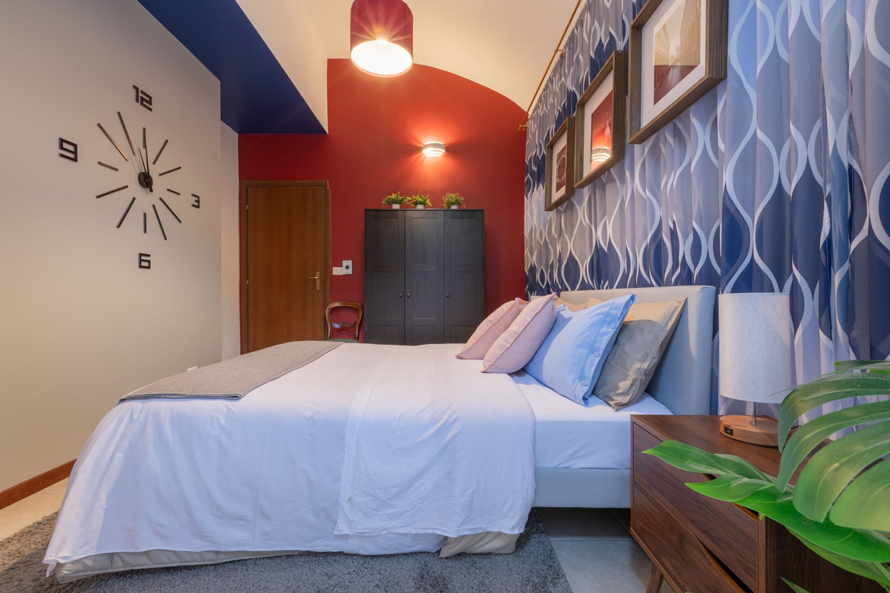 A bedroom with a bed, bedside tables, a clock, and a wardrobe.
