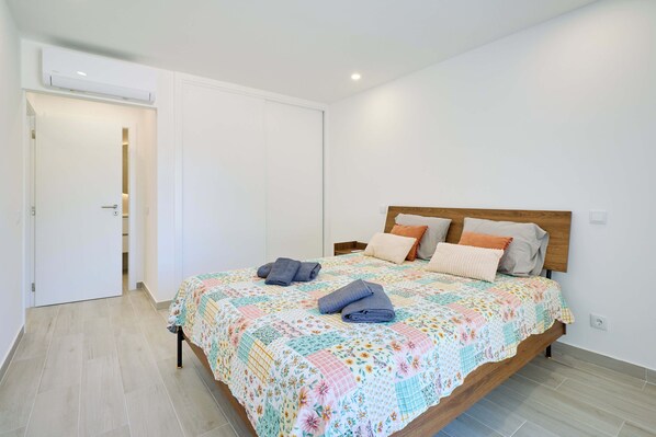 Een slaapkamer met een bed, kussens en opgevouwen handdoeken.